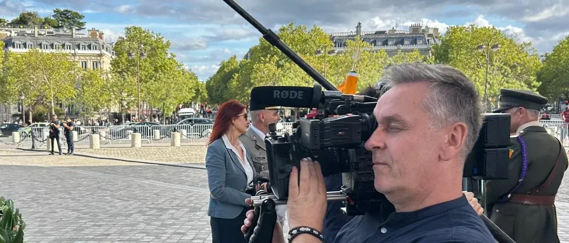 Emmet Harte filming with a broadcast camera at a ceremony